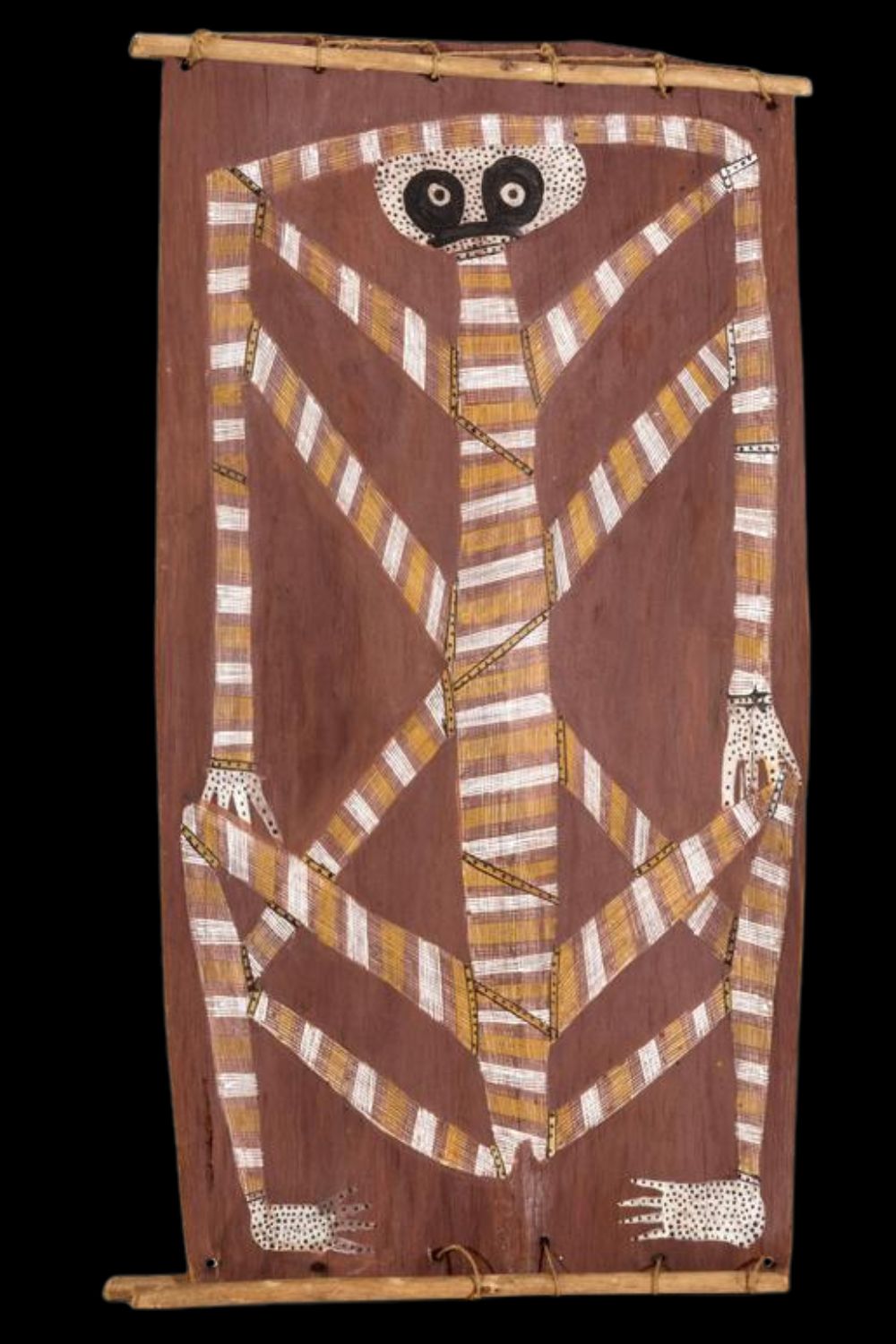 Bark painting by Aboriginal artist Mick Kubarrku depicting a stylized spirit figure with angular limbs and a dotted white face, outlined in traditional rarrk (crosshatching) using ochre tones of white, yellow, and red on a natural bark surface. The figure is centered with symmetrical, elongated arms and legs, and is framed by natural wood crossbars