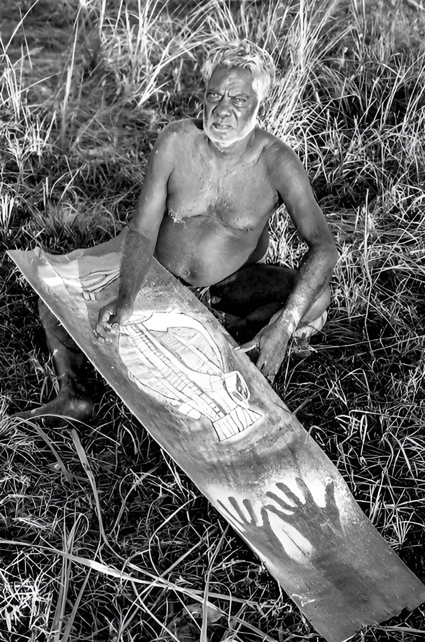 photo namatbara / Namadbara Historic black and white photo of Aboriginal artist Paddy Compass Namatbara seated outdoors with a bark painting featuring rarrk design and hand stencils, taken in Western Arnhem Land, Northern Territory