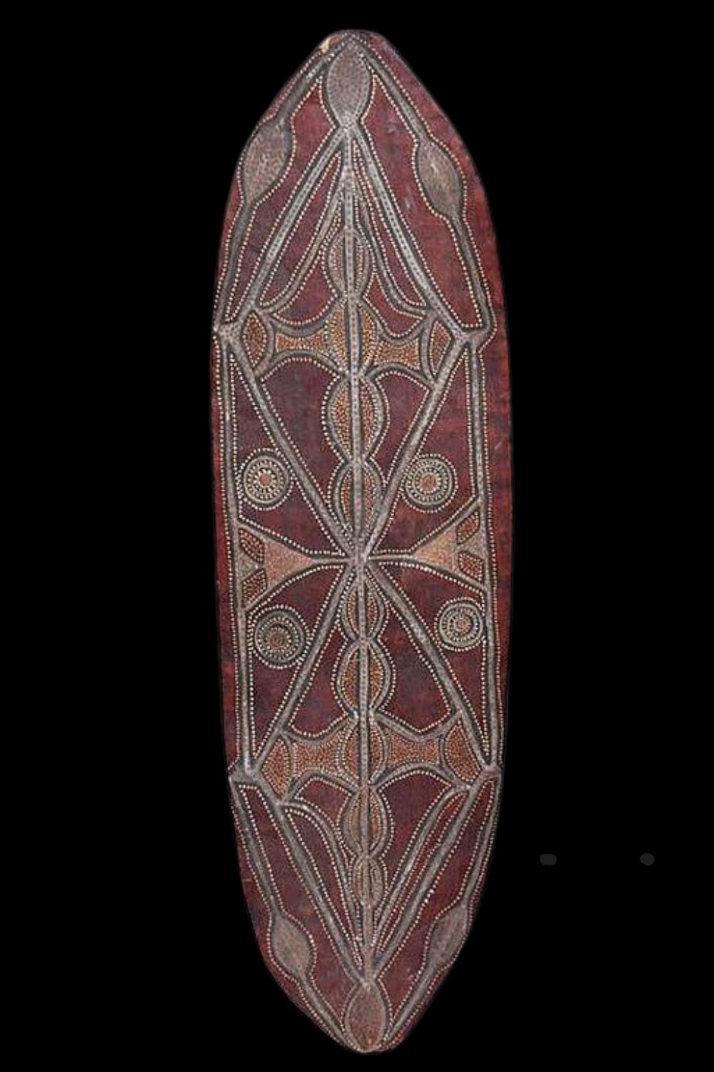 Charlie Rock ngumbe painting on an oval sheet of bark with traditional churinga designs