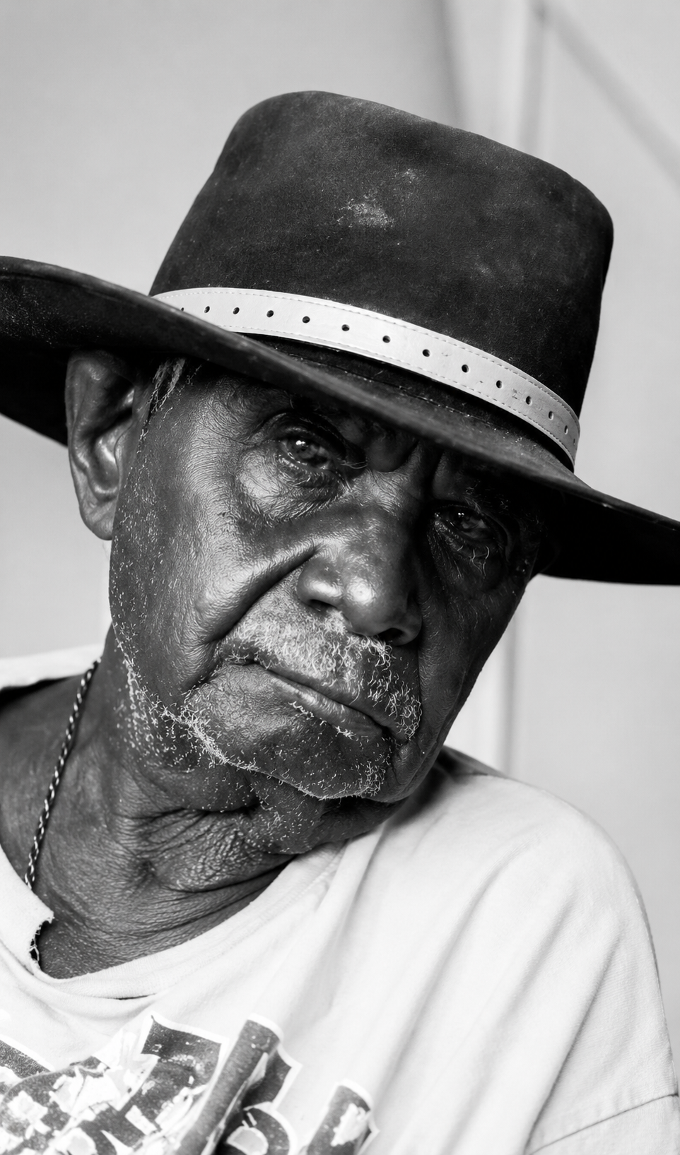 Black and white portrait photograph of East Kimberley artist Paddy Jaminji wearing a broad-brimmed hat.