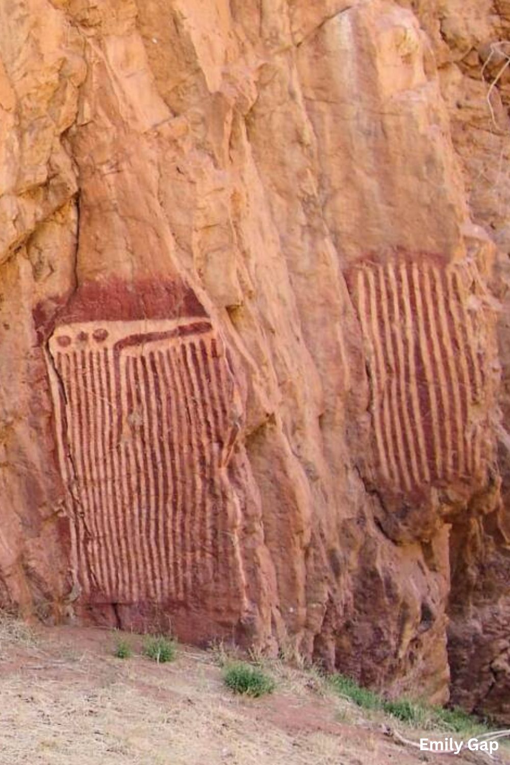 Ancient Aboriginal rock art at Emily Gap in Central Australia showing large elongated geometric motifs painted in red and white ochres on a sandstone rock face