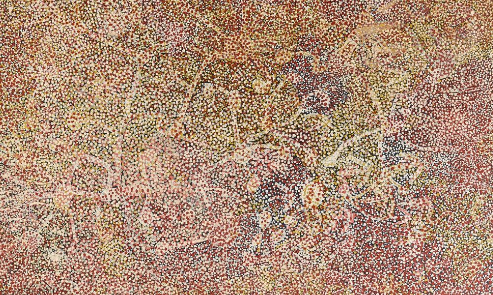 Painting by Emily Kame Kngwarreye featuring intricate fields of red, cream, yellow, and white dotting representing Wild Yam Dreaming and the ancestral landscape of Alhalker Country.