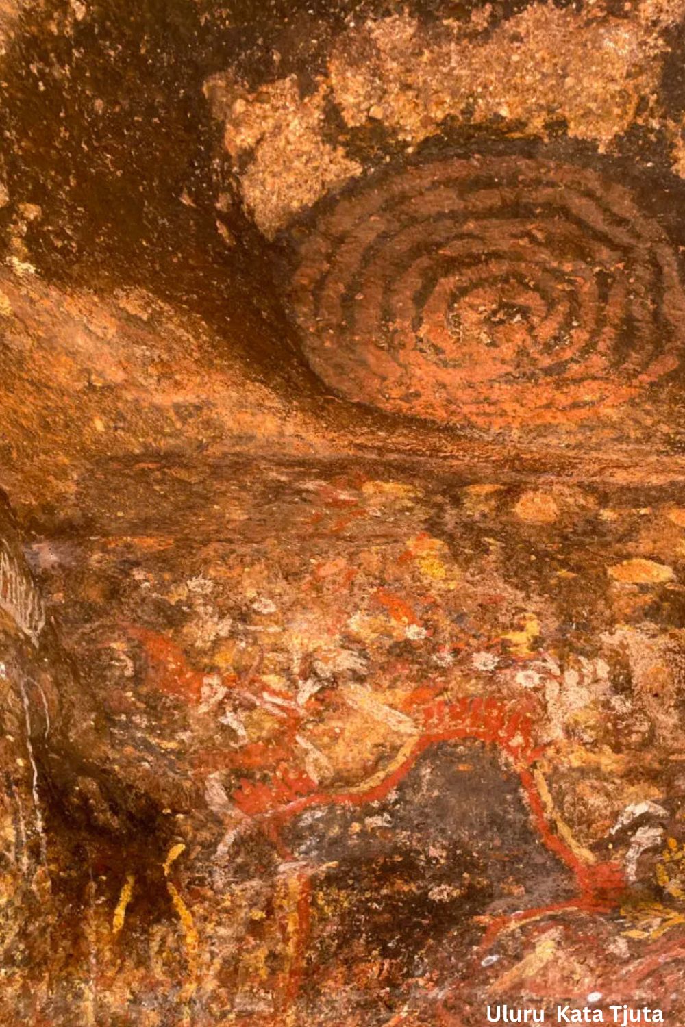 Ancient Aboriginal rock art at Uluru and Kata Tjuta featuring concentric circle motifs and ochre ceremonial imagery painted inside a sandstone rock shelter in Central Australia