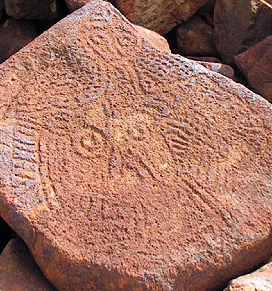 Complex geometric Murujuga rock engraving carved into volcanic stone on the Burrup Peninsula in Western Australia.