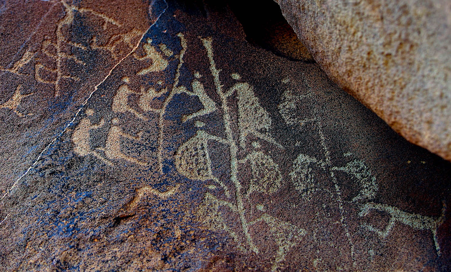 Ancient anthropomorphic engravings carved into volcanic rock within the Murujuga Cultural Landscape on the Burrup Peninsula.