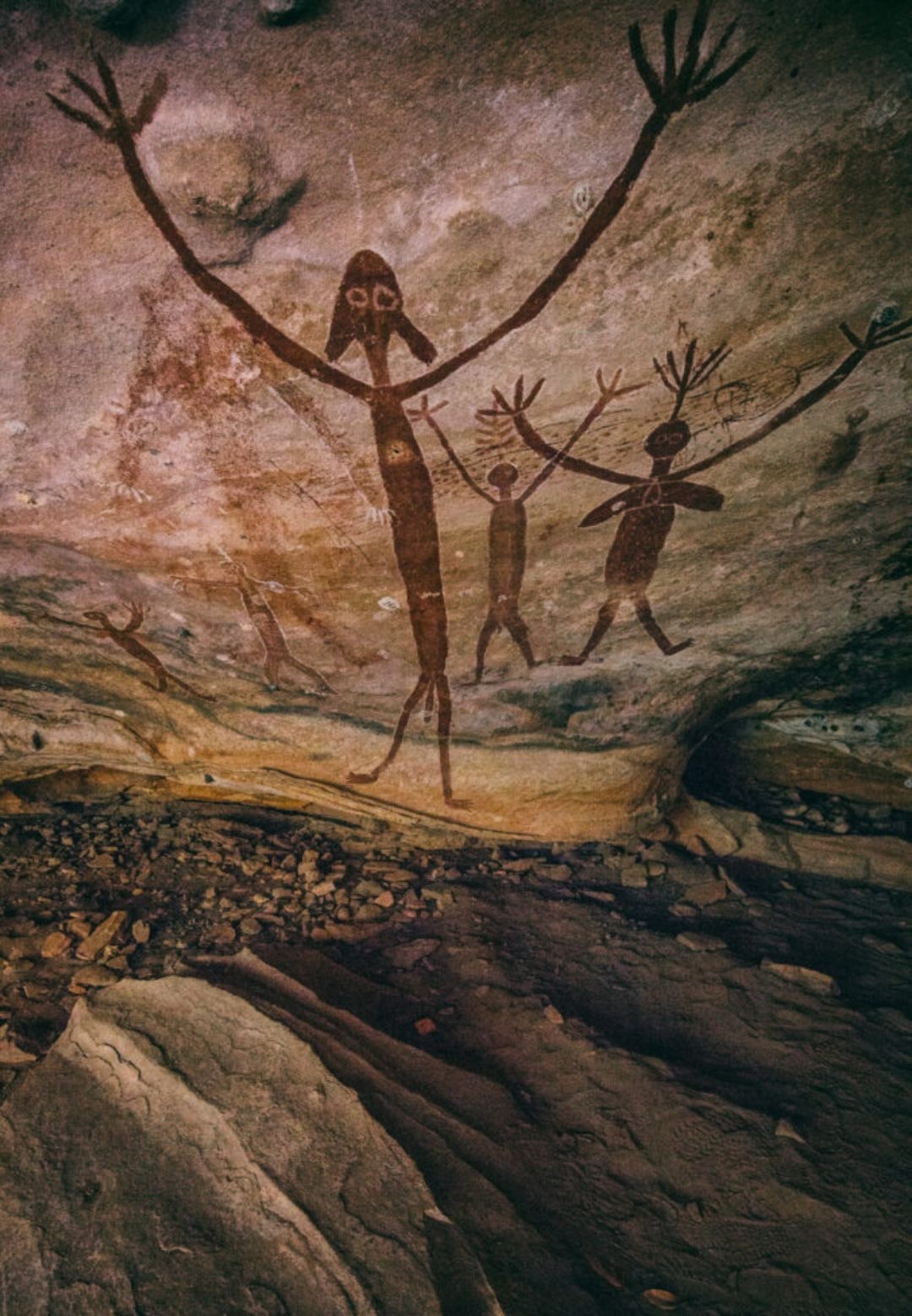 Ancient Quinkan spirit figures painted in red ochre inside a sandstone cave shelter in Cape York Aboriginal rock art tradition