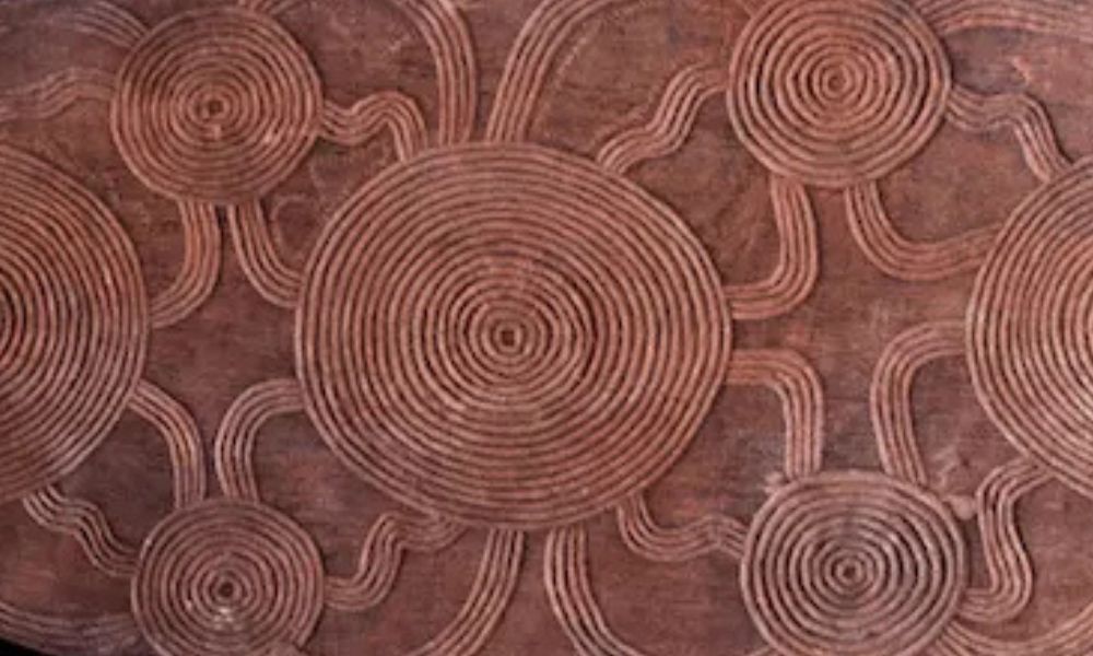 Traditional carved tjurunga featuring concentric circles and ancestral pathway motifs associated with Central Desert ceremonial traditions before Papunya painting