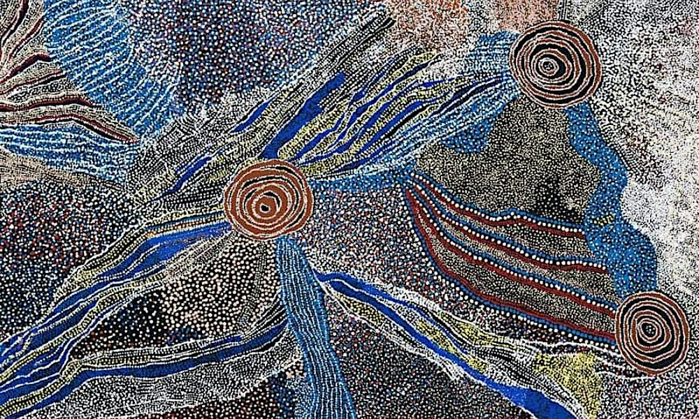 Painting by Bill Whiskey Tjapaltjarri featuring concentric circles connected by flowing blue, white, and ochre lines representing sacred sites, watercourses, and ancestral journeys across Country.