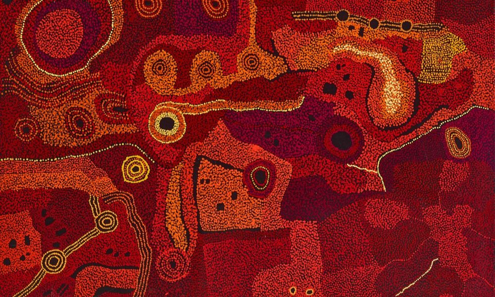 Painting by Tjungkara Ken depicting the Seven Sisters Dreaming through vibrant red, orange, and crimson dot fields, interconnected sacred sites, and ancestral pathways across the APY Lands.