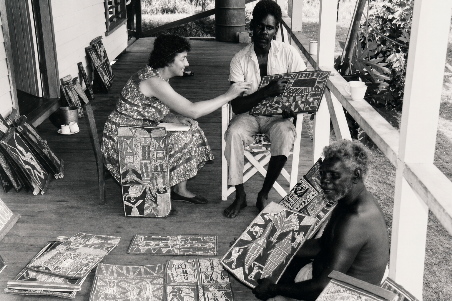Historic photograph of Groote Eylandt artists showing bark paintings to a missionary collector at Angurugu mission settlement