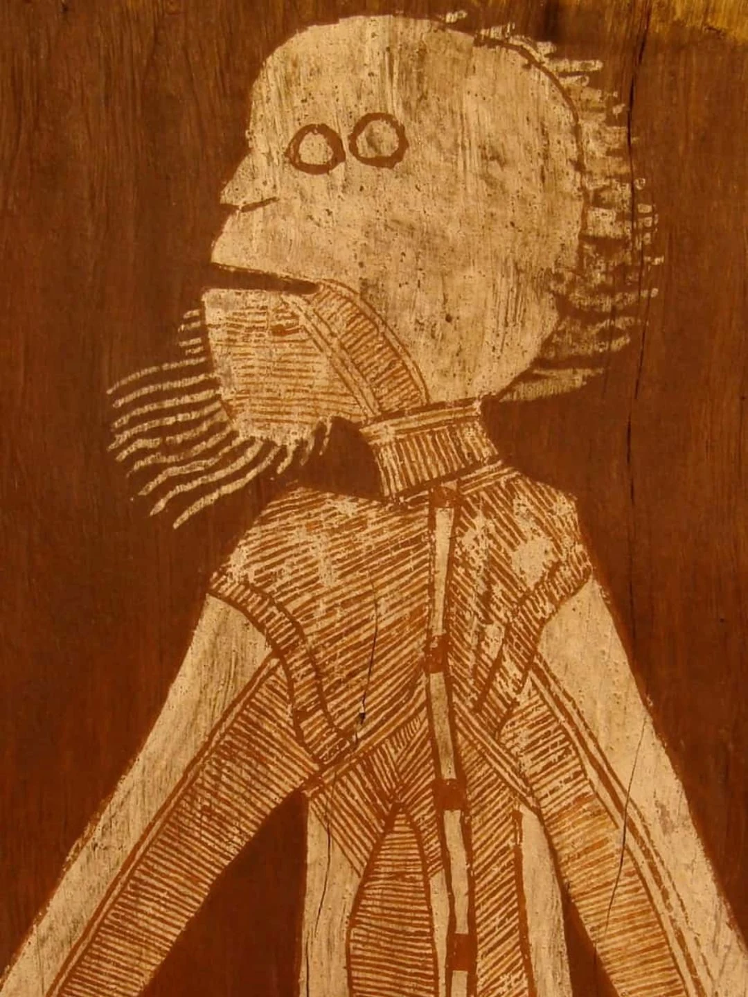 Detail of an important bark painting by Lofty Bardayal Nadjamerrek depicting a ceremonial spirit figure with fine parallel line hatching from Western Arnhem Land