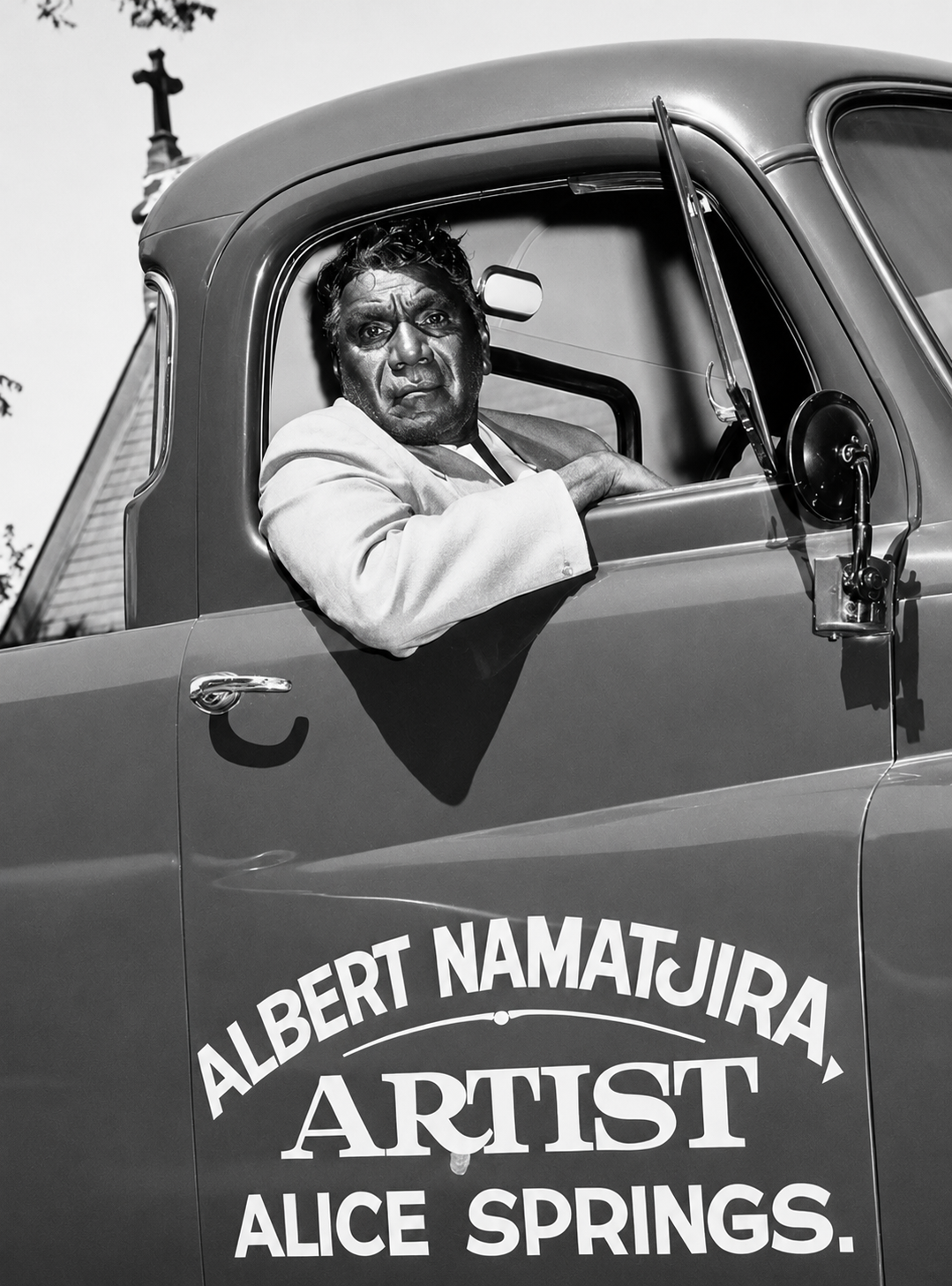 Albert Namatjira sitting in the driver's seat of his truck in Alice Springs with "Albert Namatjira Artist" painted on the door.