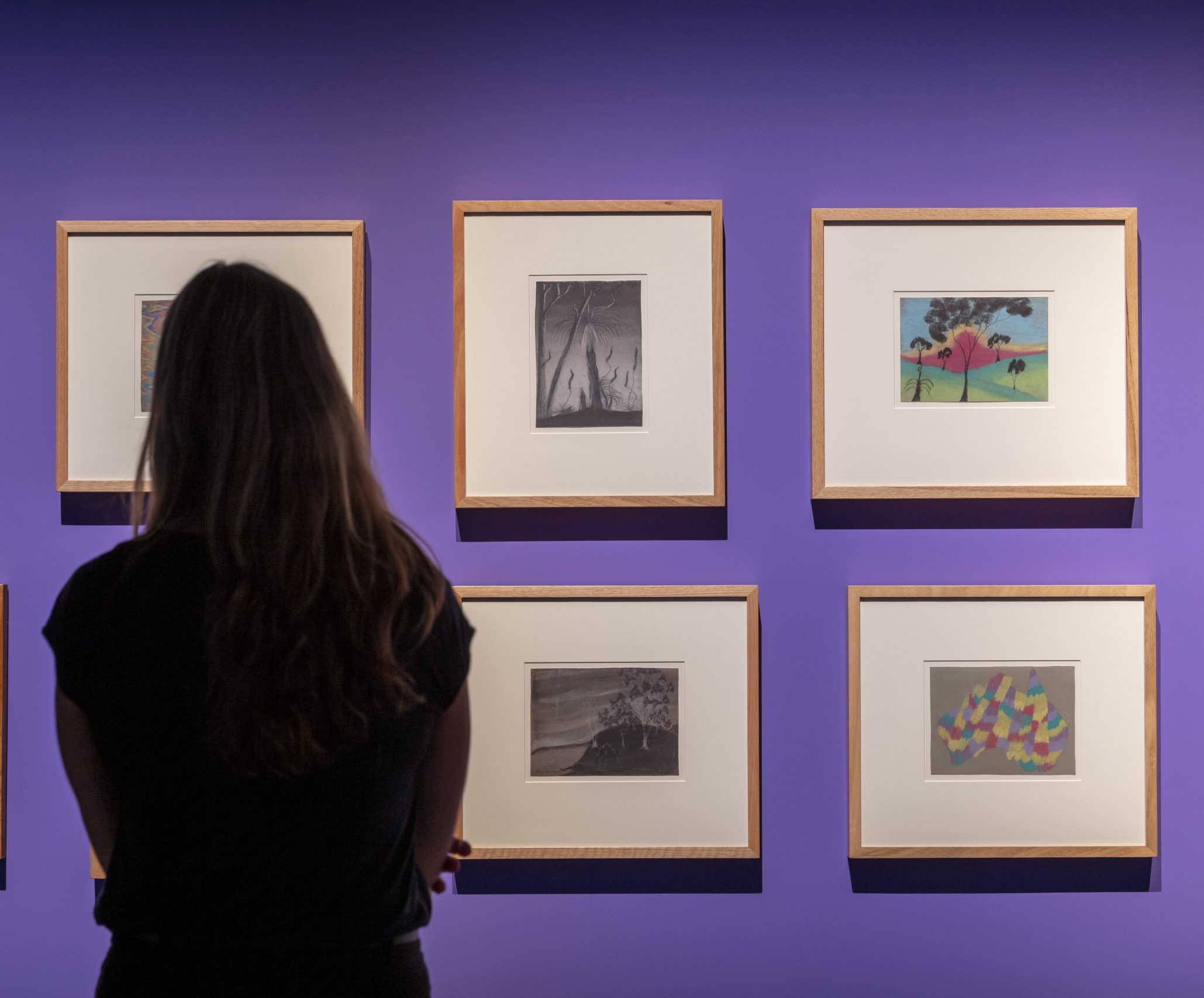 Visitor viewing Carrolup artworks displayed in a gallery exhibition in Western Australia.