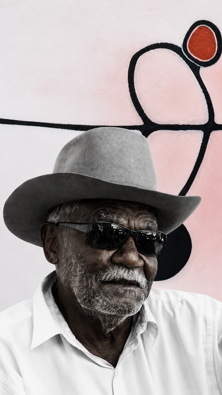 Paddy Bedford, senior Gija lawman and East Kimberley Aboriginal artist, photographed in front of one of his minimalist ochre paintings.