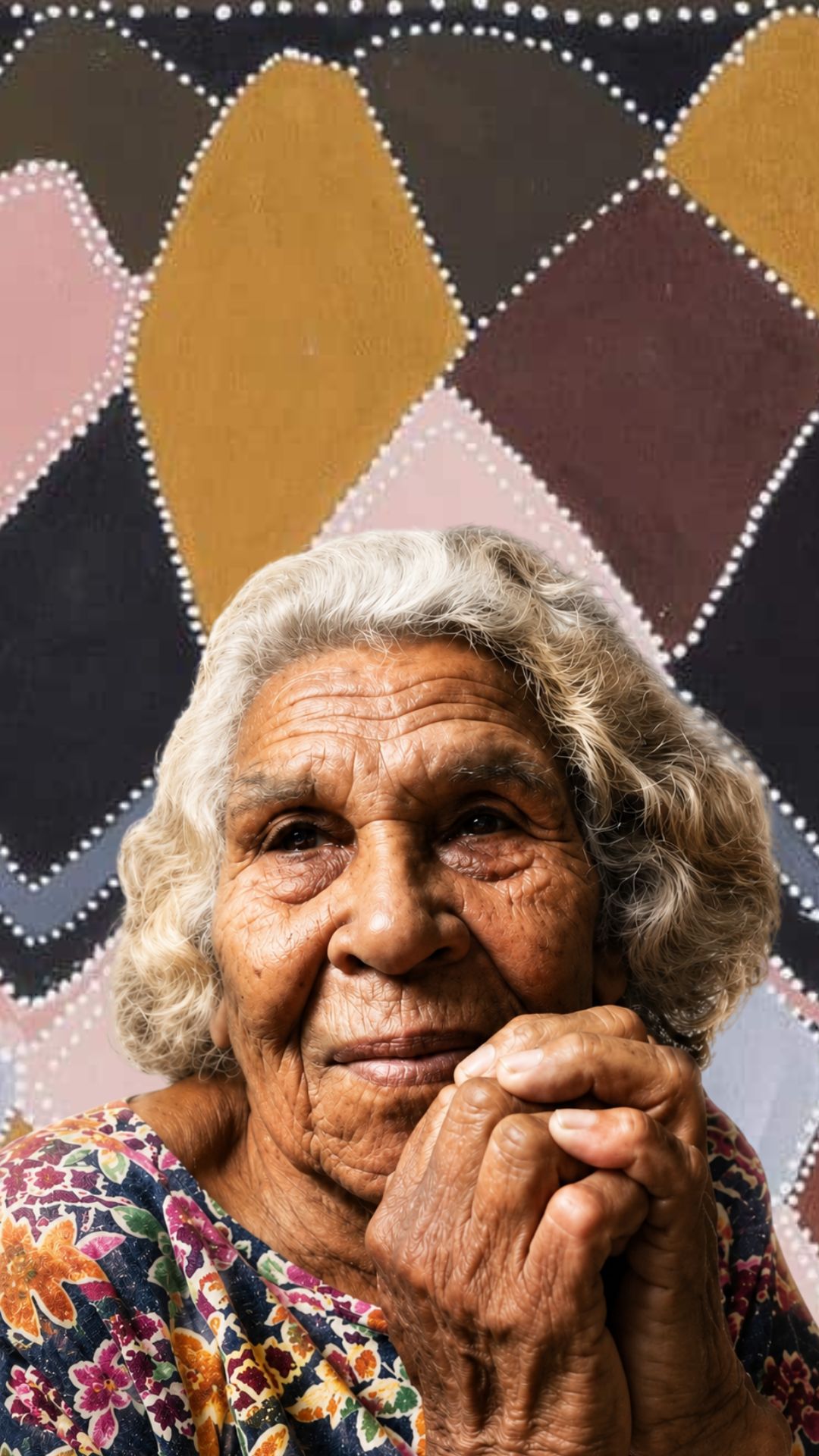 Portrait of Queenie McKenzie, Gija Aboriginal artist, shown in front of one of her East Kimberley paintings.