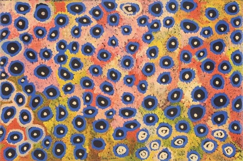 Naata Nungurrayi painting Women's Ceremony (2005), featuring vibrant blue concentric motifs scattered across a pink, yellow and ochre dotted ground representing ceremonial sites in Pintupi Country.