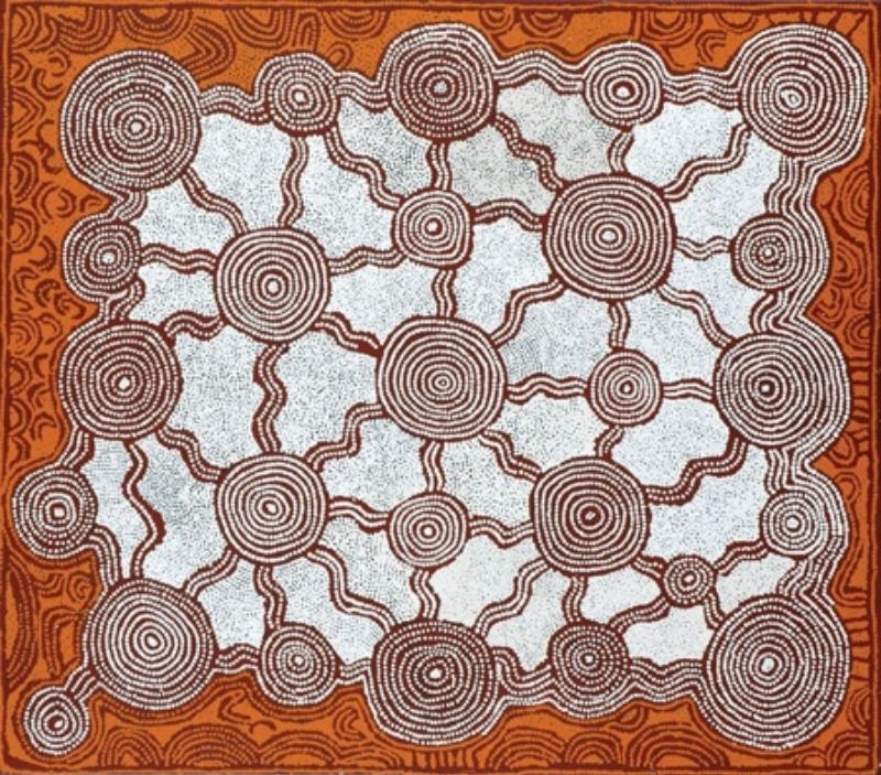 A horizontal Aboriginal painting in a restrained palette of warm terracotta, deep reddish-brown, cream and white. The centre of the painting is filled with a network of more than twenty concentric circles of different sizes, each built from finely dotted rings and connected by gently winding pathways that form a web across the composition. The background between the circles is almost entirely white, making the darker circles and connecting lines stand out with exceptional clarity. A broad terracotta border surrounds the central design, filled with flowing contour-like patterns that echo the forms inside. Thousands of tiny dots create every line and circle, producing a calm, balanced composition that resembles an aerial view of interconnected ceremonial sites across the Western Desert.