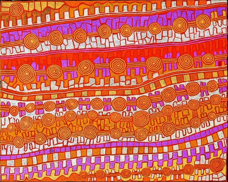 A large horizontal Aboriginal painting in brilliant desert colours of vivid orange, burnt orange, golden yellow, deep red, cream, white and vibrant lilac. Broad horizontal bands sweep gently across the canvas, each filled with repeating stepped motifs, rows of concentric circles and finely dotted geometric patterns. Three prominent rows of interconnected circles run across the painting, linked by winding pathways that resemble ceremonial routes stretching through the landscape. Lilac bands contrast dramatically with the warm oranges and yellows, while white dotted passages brighten the composition and create a shimmering optical effect. Thousands of tiny dots define every line, producing a richly layered aerial view of interconnected ancestral sites across the Western Desert.