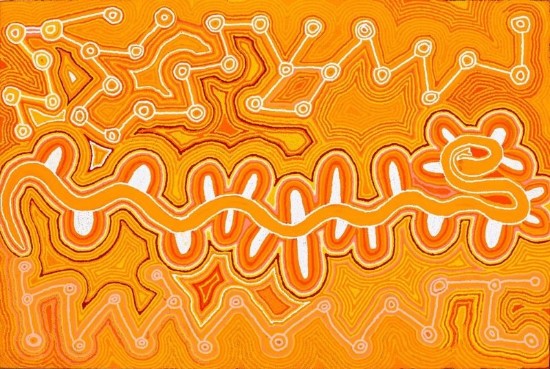 A large horizontal Aboriginal painting dominated by brilliant shades of golden yellow, vivid orange, ochre, cream and white. A broad white winding pathway snakes across the centre of the painting from left to right, ending in a large coiled circular form surrounded by short radiating loops that resemble petals or rays. Above and below this central pathway are intricate networks of small concentric circles linked by fine white travelling lines, interspersed with angular diamond-shaped motifs and contour-like patterns. Thousands of tiny dots create every line and colour transition, giving the surface a shimmering appearance. The bold contrast between the luminous orange background and the bright white central pathway creates a striking sense of movement, as though an important ancestral route is flowing through the landscape.