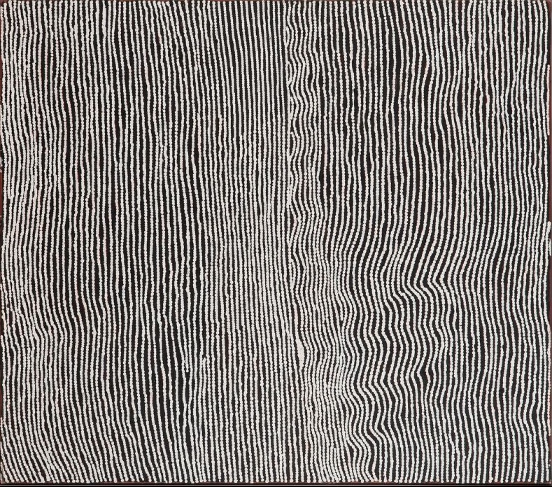 Tingari by Warlimpirrnga Tjapaltjarri, 2002. A nearly square painting in black and white. Thousands of tiny white dots form closely spaced vertical lines that flow from top to bottom across a deep black background. The lines gently bend and ripple, with one broad undulating band sweeping through the right side of the composition. The minimalist palette and rhythmic patterns create a shimmering optical effect like curtains of rain, rippling water or wind moving across the desert.