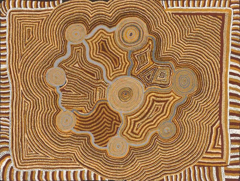 A rectangular Aboriginal painting in warm desert colours of rich chocolate brown, burnt umber, ochre, cream and white. Near the centre is a large pale ochre circle surrounded by several smaller circular motifs connected by winding grey-blue pathways, forming a network across the composition. Thousands of carefully placed cream and white dots create closely spaced contour-like lines that ripple outward around the circles like topographic map lines or waves in sand. Four angular stepped motifs sit between the circular forms, while a broad border of alternating brown and white stripes frames the painting. The overall effect is highly ordered, rhythmic and hypnotic, with intricate geometric patterns suggesting interconnected places within the Western Desert landscape.