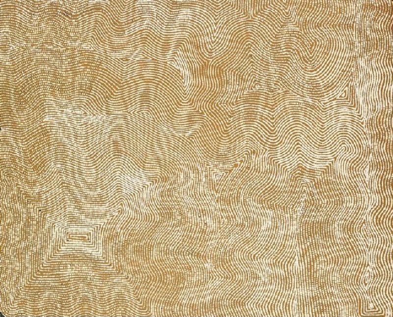 Untitled by Warlimpirrnga Tjapaltjarri, 2000. A horizontal painting in soft cream, pale ochre and warm golden brown. Thousands of tiny dots form flowing parallel lines that ripple gently across the surface, creating subtle zigzags, diamonds and meandering pathways. The delicate monochrome palette gives the painting a luminous, almost mist-like appearance, while the shimmering lines resemble wind-blown sand or sunlight moving across the desert.