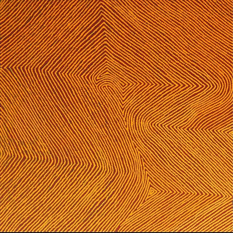 My Grandfather's Country by Warlimpirrnga Tjapaltjarri, 2010. An abstract Aboriginal painting in glowing golden ochre, burnt orange and deep reddish-brown. Thousands of evenly spaced ochre dots form continuous parallel lines that sweep diagonally across the canvas, converging into sharp angles, zigzags and broad geometric pathways. The warm earth colours create a luminous, shimmering surface that evokes the ridges, valleys and ancient ceremonial routes of the Western Desert when viewed from above.