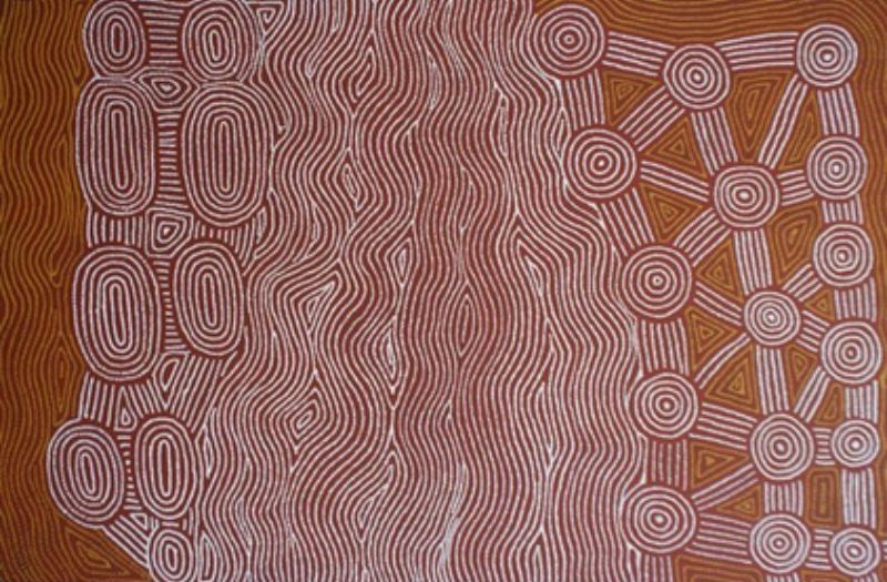 Tingari at Wilkinkarra by Warlimpirrnga Tjapaltjarri, 2000. A horizontal painting in rich reddish-brown, white and ochre. The centre is filled with dense vertical bands of finely dotted white lines that ripple gently from top to bottom. On the left, elongated oval motifs are stacked in vertical columns, while on the right, concentric circles are linked by straight pathways and triangular forms. The contrast between flowing linear patterns and traditional ceremonial symbols creates a striking sense of rhythm and movement.