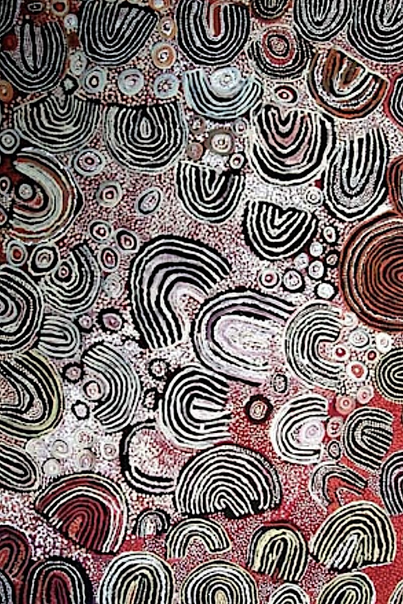 Close-up detail of a Naata Nungurrayi painting showing thick acrylic paint, delicate dotting and subtle variations of ochre, cream, black and muted red
