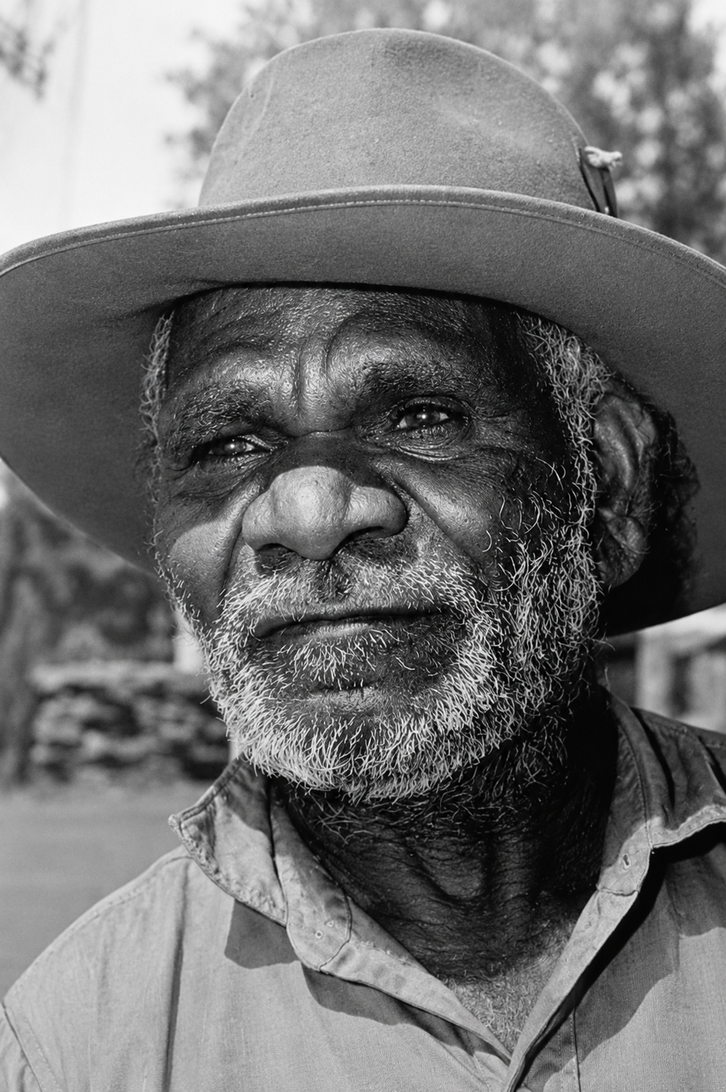 Portrait of Nosepeg Tjupurrula, senior Pintupi ceremonial leader and founding Papunya artist, wearing a broad-brimmed hat.