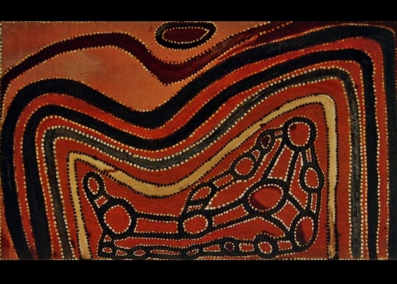 Rover Thomas ochre painting with concentric wavy bands of black, red and yellow surrounding a central group of linked circles and elongated forms outlined with white dots.