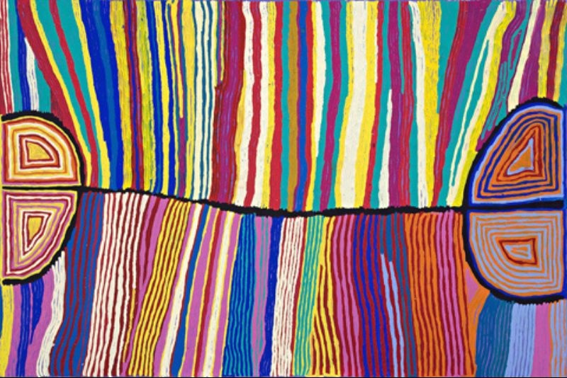 Colourful Judy Watson Napangardi painting with dense vertical bands of red, yellow, blue, green, pink and white divided by a black horizontal line connecting large semicircular forms on either side.