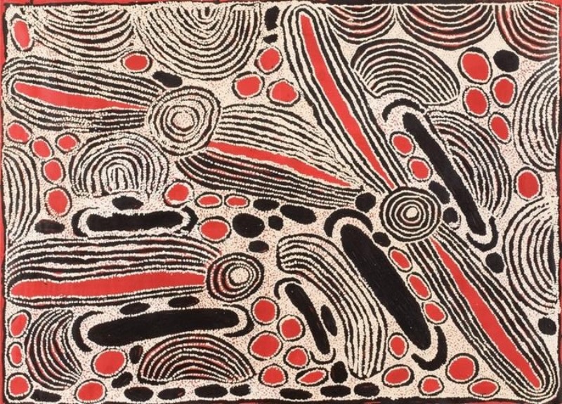 Red, black and white Aboriginal painting by Ningura Napurrula densely filled with curved parallel lines, concentric circles and elongated oval forms. Bright red shapes and long red bands are scattered throughout the composition alongside solid black forms, while sweeping striped shapes cross diagonally and horizontally across the canvas.