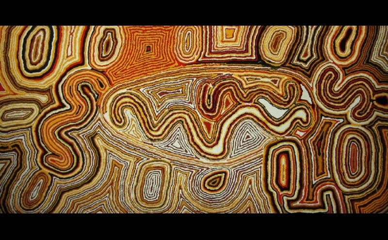 Tjumpo Tjapanangka Wilkinba Near Lake Mackay 1993, with densely layered winding and concentric lines in ochre, orange, black and white forming interconnected shapes across the canvas.