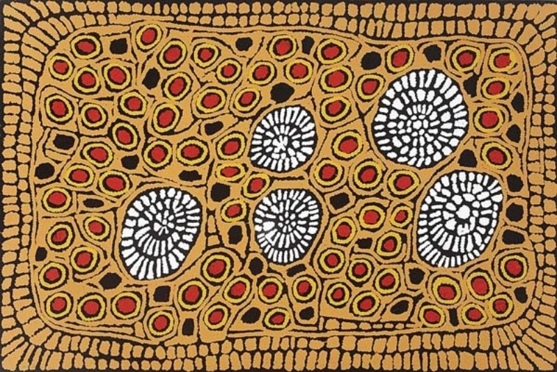 Ochre, black, red and white Aboriginal painting by Ningura Napurrula enclosed by a broad rectangular border of small ochre blocks. The interior is densely filled with dozens of small red-centred circular motifs outlined in ochre, scattered black shapes, and five prominent black oval forms filled with radiating white marks.