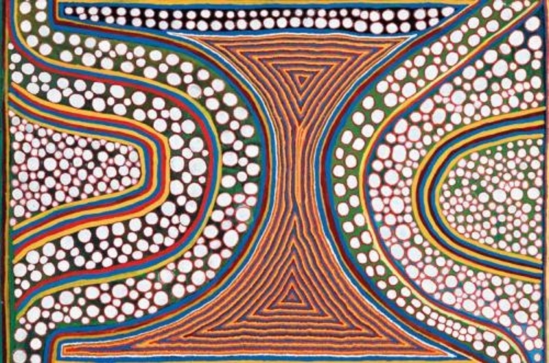 Boxer Milner’s Wanarlapirri on Sturt Creek (1999), with sweeping curved bands, large fields of white dots and a central hourglass-shaped geometric form in brown, orange, blue and green.