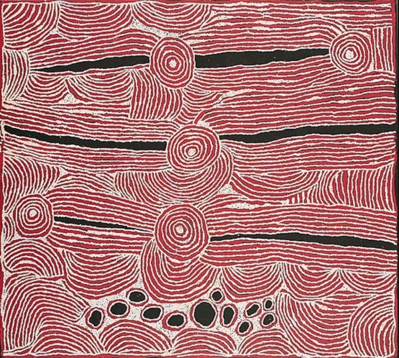 Red, black and white Aboriginal painting by Ningura Napurrula dominated by broad horizontal bands of closely spaced white lines over a red ground. Irregular black channels run through the bands, several concentric circles punctuate the composition, and curved striped forms fill the spaces between them. A cluster of black oval shapes appears near the lower centre.
