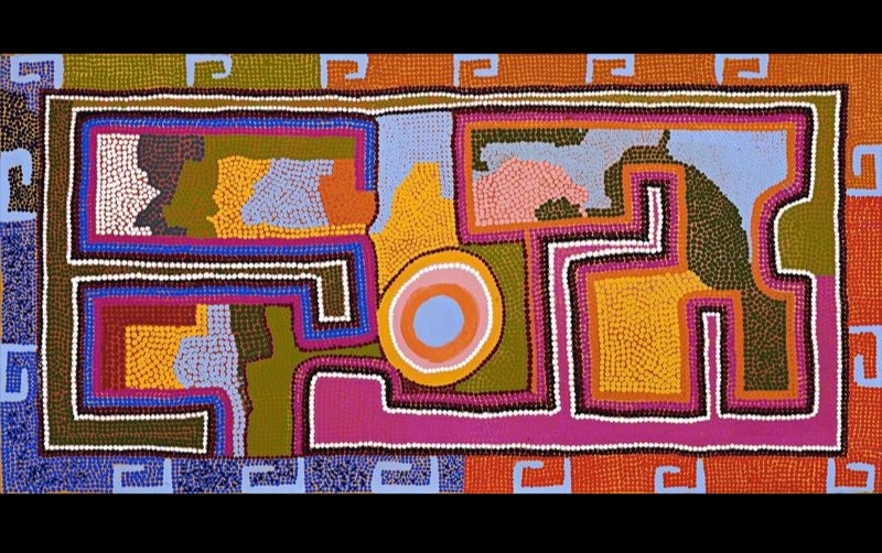 Boxer Milner’s Purkitji (Sturt Creek) (2005), featuring interlocking angular pathways outlined in white, black and pink around fields of blue, green, yellow and orange, with a concentric circle near the centre.