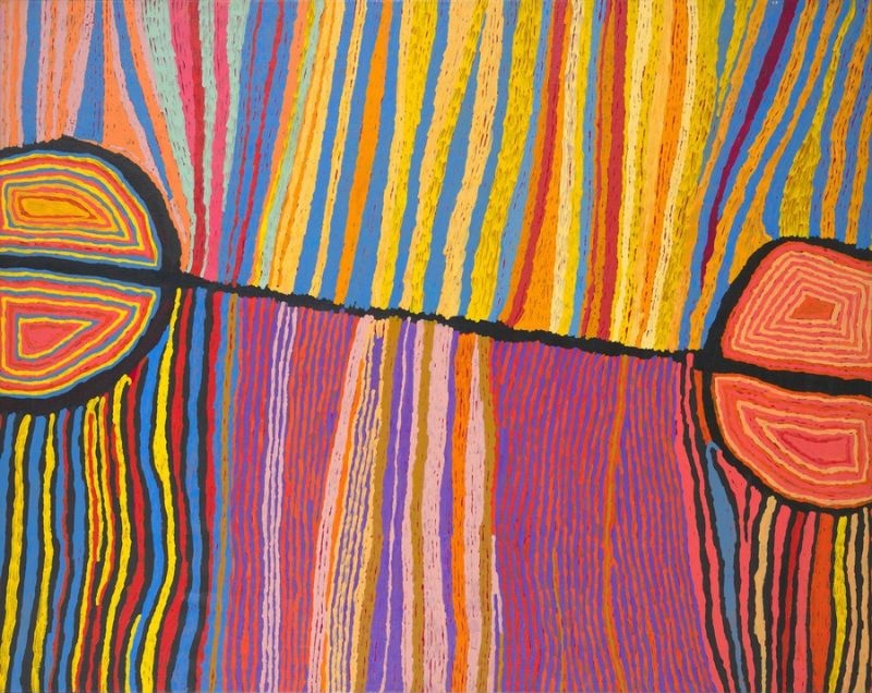 Colourful Judy Watson Napangardi painting with dense vertical bands of yellow, blue, pink, orange, purple and red crossed by a black line connecting two large semicircular forms.
