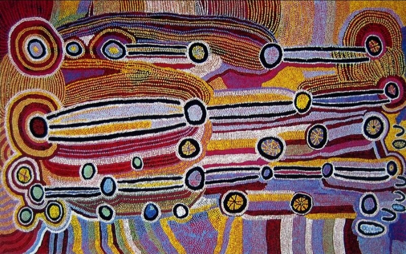 Maggie Watson Napangardi painting with long white, black and red linear forms connecting numerous concentric circles across dense fields of red, yellow, purple, blue and ochre dots.