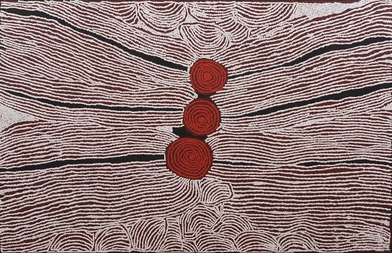 Large black, white and red Aboriginal painting by Ningura Napurrula dominated by three red concentric circles arranged vertically through the centre. Dense bands of fine white parallel lines sweep horizontally across a dark ground, separated by irregular black channels, with clusters of smaller curved forms along the upper and lower edges.