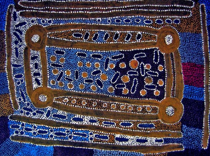 Maggie Watson Napangardi painting with a large rectangular ceremonial design of connected circles and parallel lines, surrounded by dense blue, white, brown and black dot patterns.