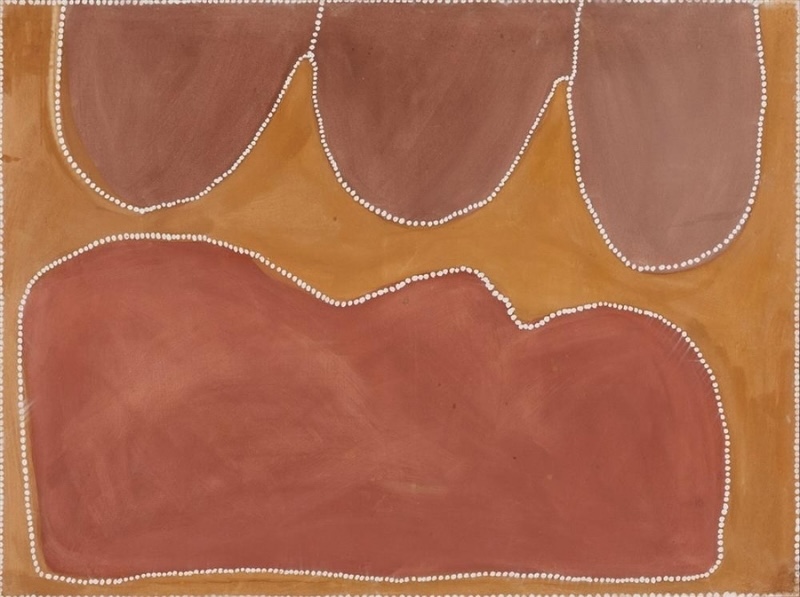 Rover Thomas painting of Country in muted pink, red-brown and golden ochre. Three large rounded mauve-brown shapes hang from the upper edge above a broad red-brown form filling the lower half. A branching golden ochre area winds between them, while rows of small white dots trace every boundary and frame the canvas.
