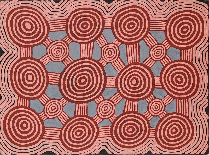Ronnie Tjampitjinpa’s Tingari Designs (Site of Pangpanga) (1997), featuring large pink and red concentric circles connected by parallel lines, with smaller circular forms arranged across a blue-grey ground.