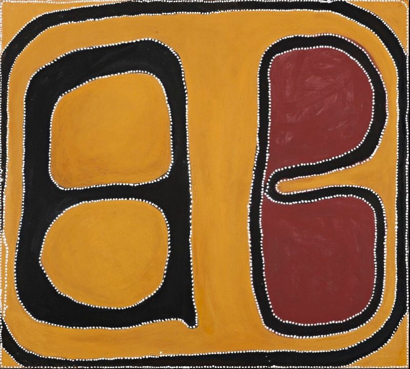 Abstract Aboriginal painting dominated by a golden ochre background. Thick black bands form two large enclosed shapes, one on the left containing two stacked ochre ovals and one on the right surrounding two deep red rounded forms connected by a narrow curved passage. The composition is framed by a broad black border, and every major shape is outlined with evenly spaced white dots, creating strong contrast between the black, ochre, red and white colours.