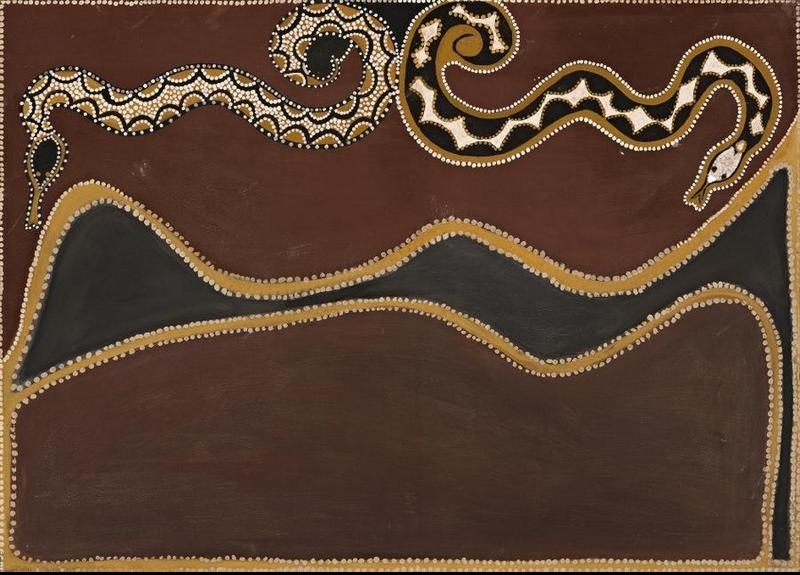 Rover Thomas painting with two patterned snakes winding across the top of a dark brown ochre field. One snake is decorated with cream, yellow and black scalloped patterns, while the larger snake has a curling body marked with bold black and cream triangles. Below them, a long black wavy form edged in golden ochre and white dots stretches across the canvas.