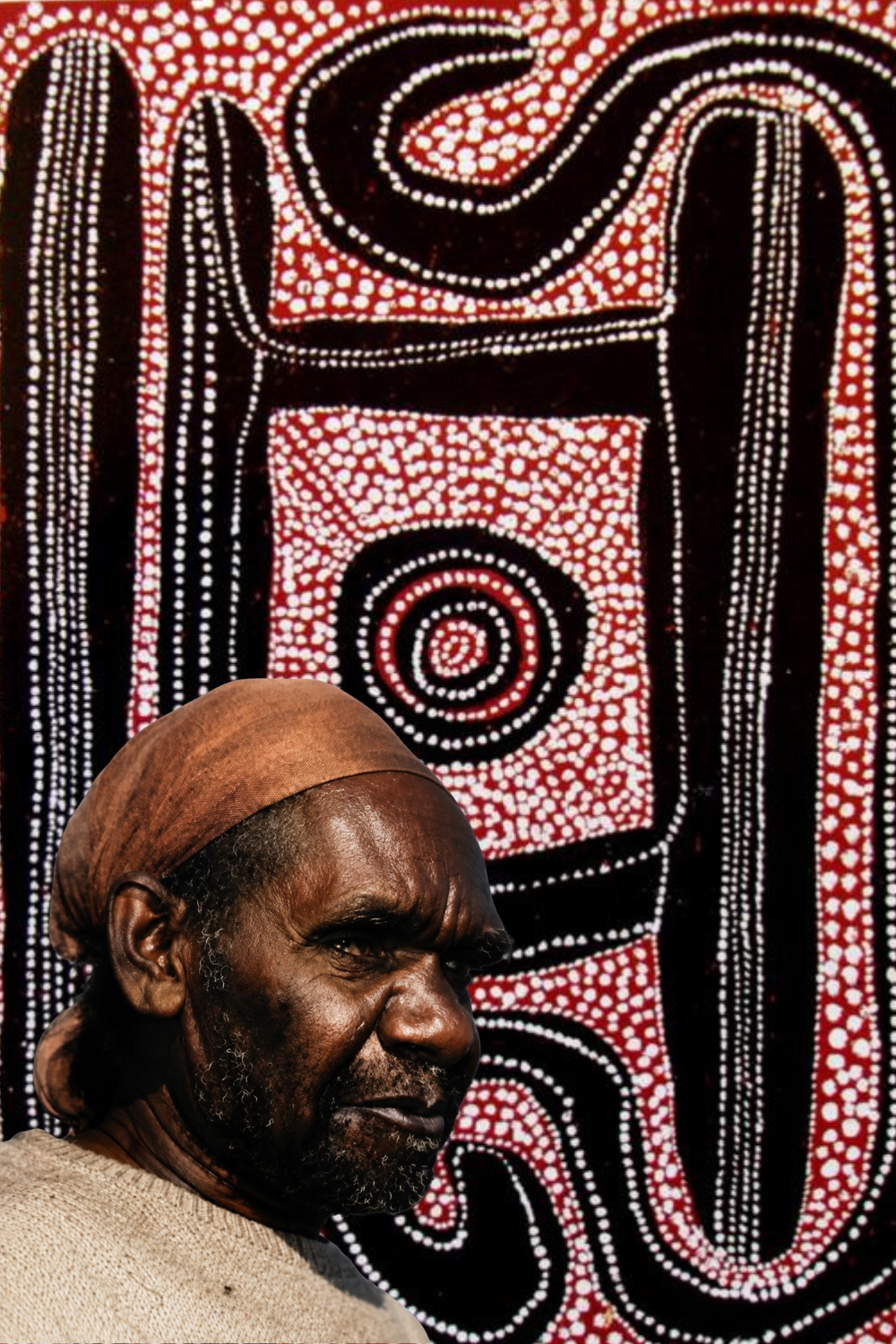 Uta Uta Tjangala with an early Pintupi painting featuring bold ceremonial forms and dense dotting.