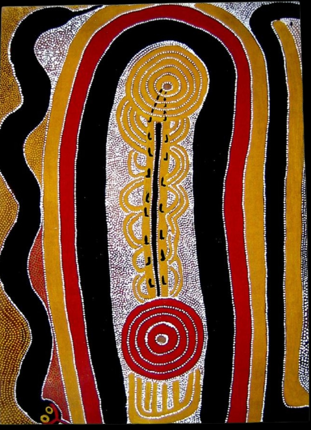 Sunfly Tjampitjin painting with two concentric circular forms connected by a long central pathway, surrounded by broad bands of black, red and ochre with fine white dotting.
