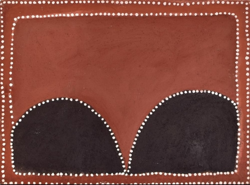Rover Thomas Hills at Bottle Tree Creek, 1995, natural earth pigments on linen, depicting two dark rounded hills against a red ochre ground.