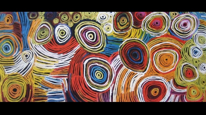 Large Minnie Pwerle painting filled with brightly coloured concentric circles and sweeping curved bands in red, yellow, green, blue, orange, pink, white and black.